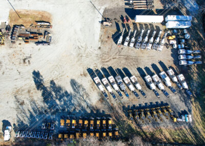 Top-down view of a service provider's fleet of construction machinery and trucks in a yard.